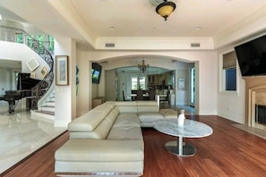 Relax in a spacious living area with a comfortable sofa, fireplace, and grand staircase.