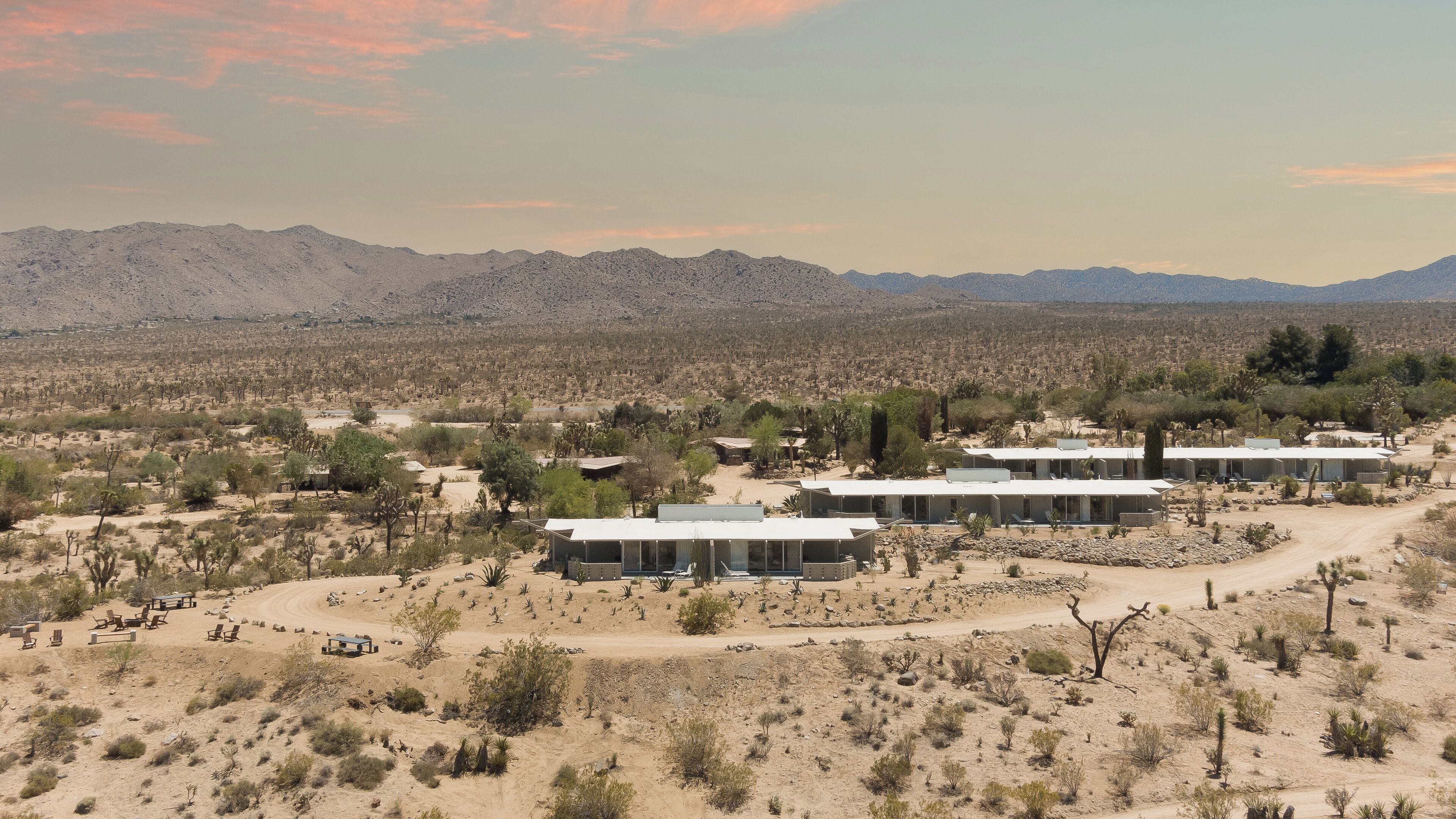 Un paysage désertique avec une rangée de bâtiments blancs, probablement un hôtel, caractérisé par un design simple et moderne, avec de grandes fenêtres et des toits plats.