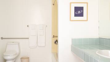 Un baño con inodoro, dos toallas, un cuadro enmarcado y un lavamanos con azulejos azules.