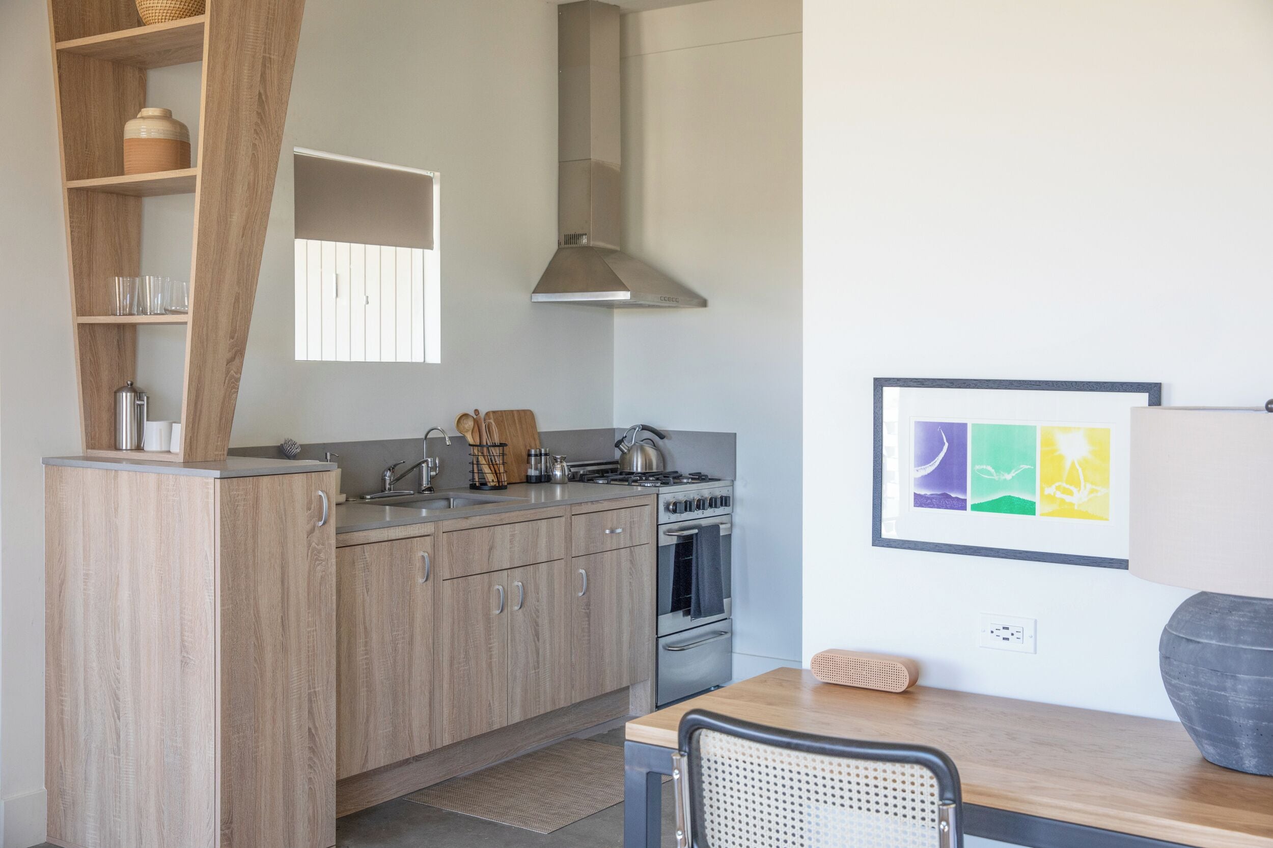 A modern kitchen with wooden cabinets, stainless steel appliances, and a window above the sink.