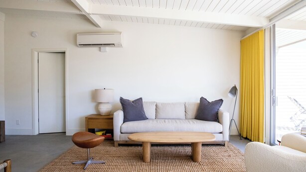 A modern living room with a white sofa, a wooden coffee table, and a brown leather chair. - The Bungalows by Homestead Modern at The Joshua Tree Retreat Center (Joshua Tree)