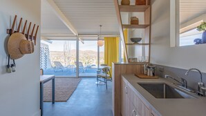 Una cucina moderna con una grande finestra, un'area pranzo con sedie e vista sull'esterno.