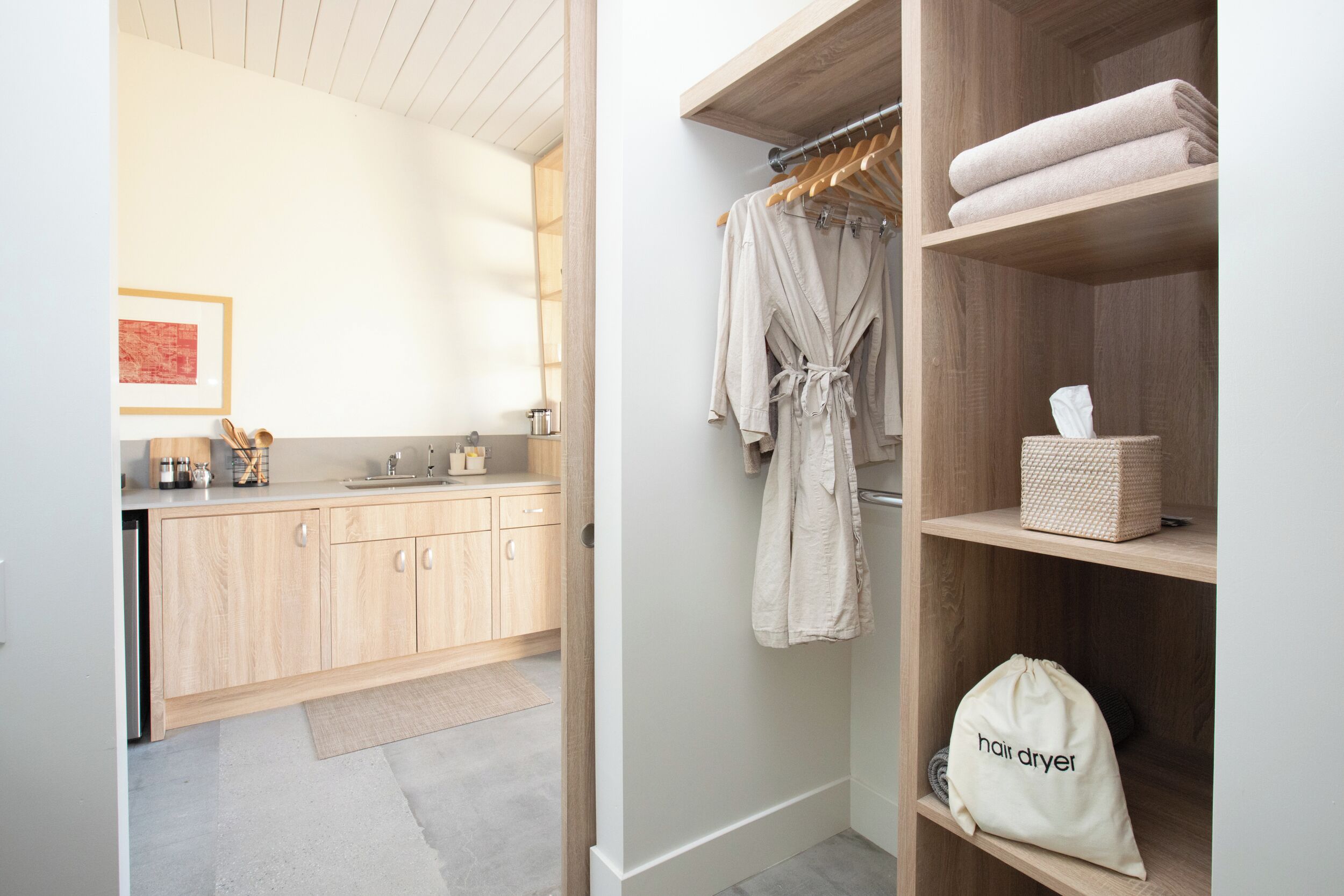 Une salle de bain moderne avec des meubles en bois, un porte-serviettes et un sac pour sèche-cheveux.