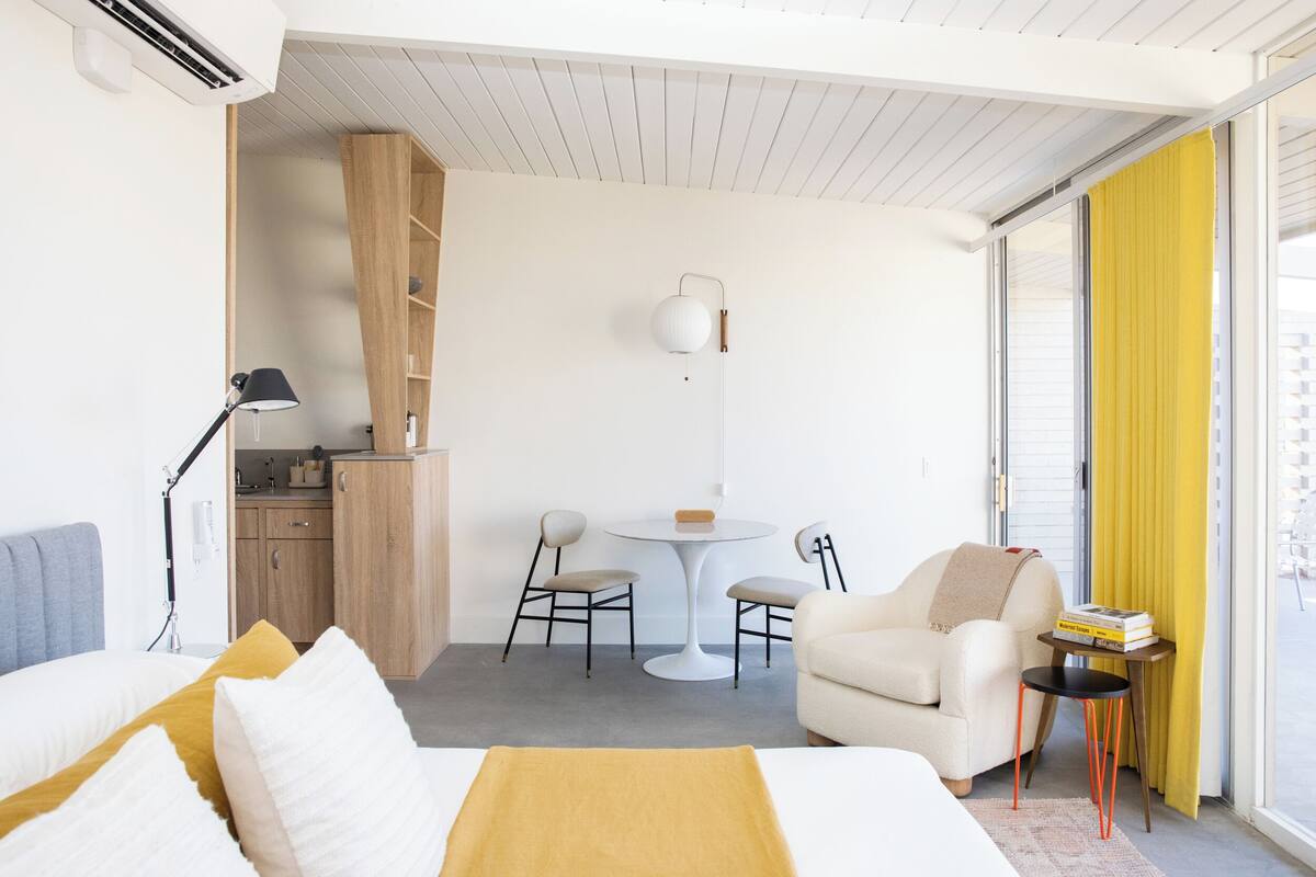 Ein modernes Hotelzimmer mit Bett, Schreibtisch, Stuhl und einer Sitzecke.