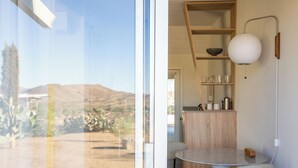 Una cucina moderna con un tavolo rotondo e sedie, una mensola in legno e una lampada a sospensione bianca.