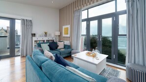 Una sala de estar moderna con un sofá azul, una mesa de centro blanca y vistas de la ciudad a través de grandes ventanales.