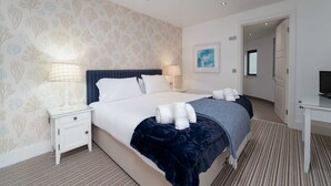 Una habitación de hotel con una cama grande, dos mesitas de noche, un escritorio y un espejo.