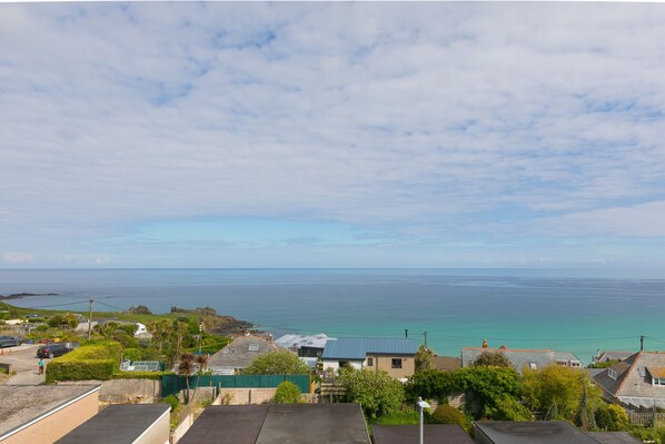 A coastal residential area with houses, a clear sky, and the sea in the background.