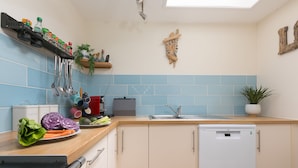 A kitchen with a dishwasher, a sink, a wooden countertop, and a blue-tiled backsplash. - Porthmeor View, St Ives  – Sleeps 8 – On-Site Parking for Two Cars – Sea Views (St Ives)