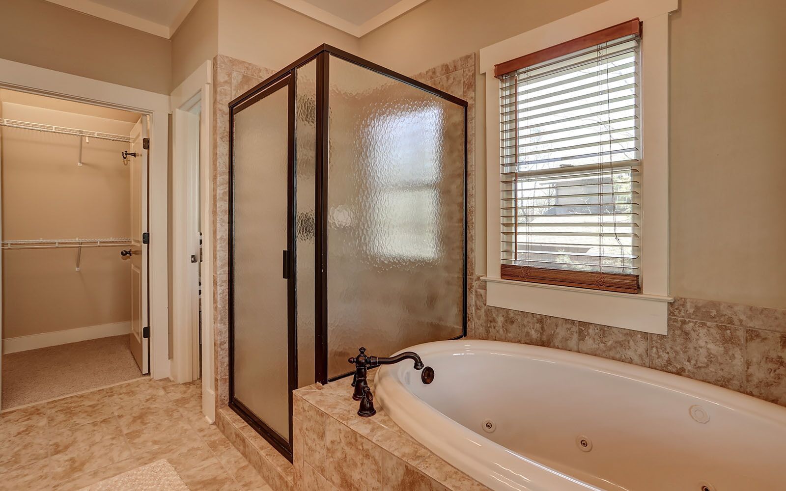 Un baño con cabina de ducha, bañera y ventana con persianas.