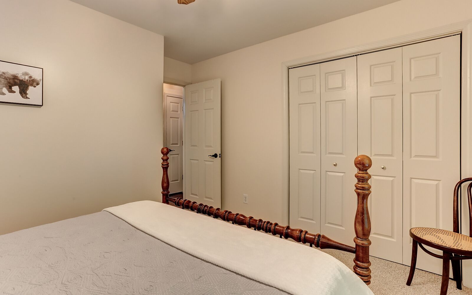 A bedroom with a bed, a chair, and two doors.