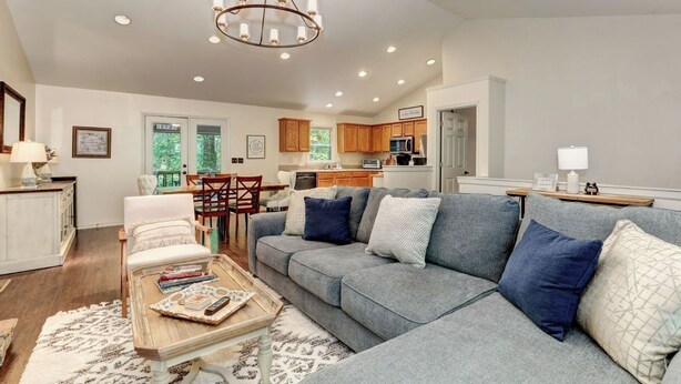 A spacious living room with a grey sofa, wooden dining table, and a chandelier. - Cozy Retreat with Fireplace, Netflix & Easy Ramp Access - Deer View Retreat (Jasper)