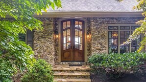 A stone house with a wooden front door, a stone staircase, and a well-maintained garden. - Eagles View - Gorgeous Mountain Views + Luxury Interiors + Telescope + Library (Dawsonville)