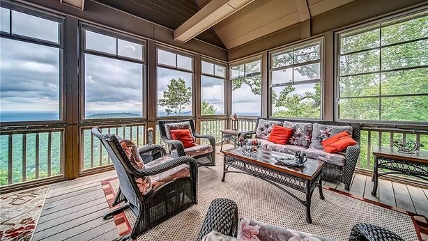 A covered outdoor seating area with wicker furniture and a view of the landscape. - Eagles View - Gorgeous Mountain Views + Luxury Interiors + Telescope + Library (Dawsonville)