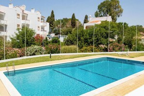 A rectangular swimming pool with clear blue water, surrounded by a tiled deck.