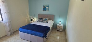 A bedroom with a bed, nightstands, a lamp, and a painting on the wall.