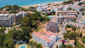 An aerial view of a coastal hotel area with multiple buildings, a swimming pool, and a beach in the background. - Apartment - Sleeps 2, Parking & Pool Access (Albufeira)
