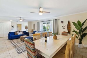 A spacious living area with a dining table, sofas, and a large plant.