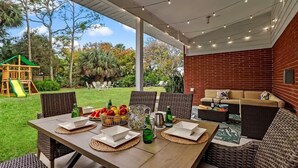 An outdoor patio with a dining table set for four, surrounded by wicker chairs. - BIG Backyard w/Terrace|Dining|Games | 6min2Beach (St. Augustine)