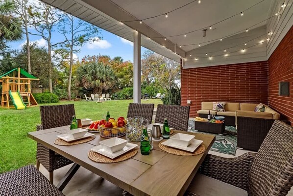 An outdoor patio with a dining table set for four, surrounded by wicker chairs.