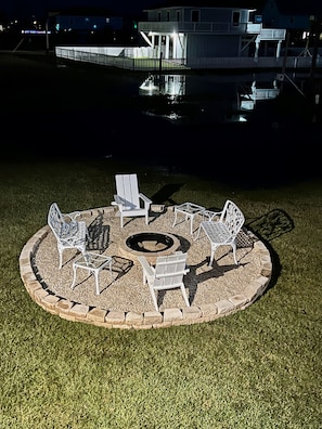 Relax by the fire pit in a serene outdoor seating area surrounded by a low wall and water views.