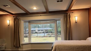 Un dormitorio con una ventana grande, una cama y una silla.