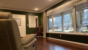 Una habitación con un ventanal grande, una silla y suelo de madera.
