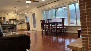Una cocina amplia con electrodomésticos modernos, un comedor con sillas de madera y grandes ventanales con vistas al exterior.
