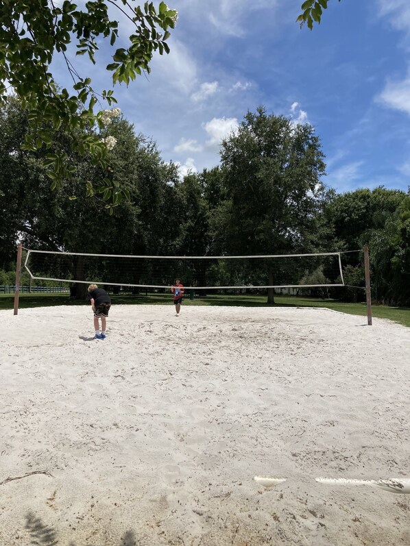 Una cancha de voleibol con red, rodeada de árboles y un cielo despejado.