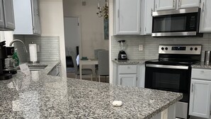 Eine moderne Küche mit Granit-Arbeitsplatten, Edelstahlgeräten und weißen Schränken.