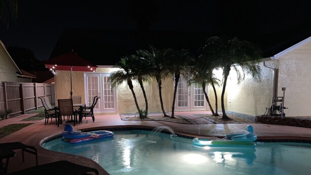 Ein Schwimmbecken mit zwei aufblasbaren Spielzeugen, eine Terrassenfläche mit Stühlen und ein überdachter Sitzbereich.