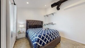 Une chambre à coucher avec un grand lit, une table de chevet avec une lampe et une armoire.