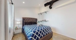 Une chambre à coucher avec un grand lit, une table de chevet avec une lampe et une armoire.