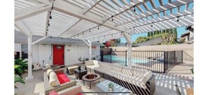 A covered outdoor area with seating, a pool, and a red door. - Cute One Story Residence 3 bedroom with pool (Canoga park)