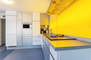 A modern kitchen with white cabinetry, a microwave, a coffee maker, and a yellow countertop.