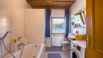 Ein Badezimmer mit Badewanne, Toilette und Waschmaschine.