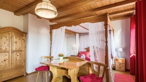 Ein Zimmer mit Holzboden, einem hölzernen Bett mit Baldachin, einem Schreibtisch aus Holz, einem Stuhl und einem Kleiderschrank.