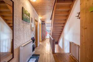 Un pasillo interior de madera con una escalera, un radiador y una puerta.