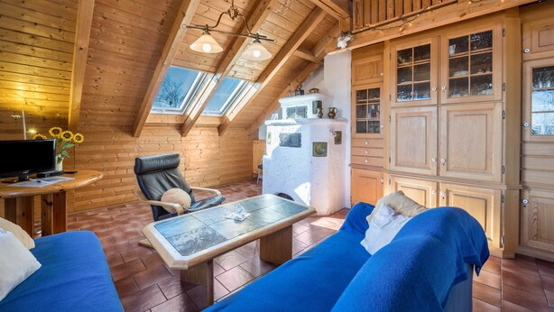 Ein gemütliches Blockhaus-Interieur mit Essbereich, einer Couch, einem Fernseher und einer Küchenzeile.