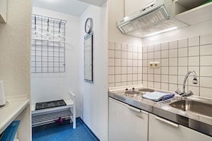 Una cucina compatta con lavandino, fornelli e un orologio appeso al muro.