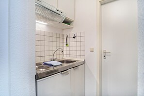 Una cucina compatta con piano cottura integrato, lavello e sistema di ventilazione a soffitto.