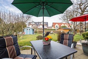 Un patio con mesa, sillas y un paraguas verde.