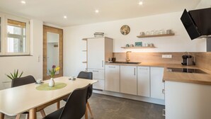 Uma cozinha moderna com armários brancos, bancada de madeira e forno embutido.