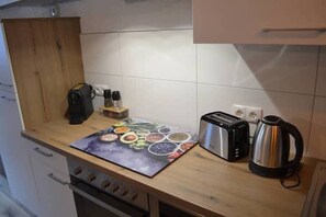 A kitchen with a toaster, kettle, and a mat with food illustrations. - Apartment "Andy's Bergblick" with Mountain View, Wi-Fi & Balcony (Leutasch)