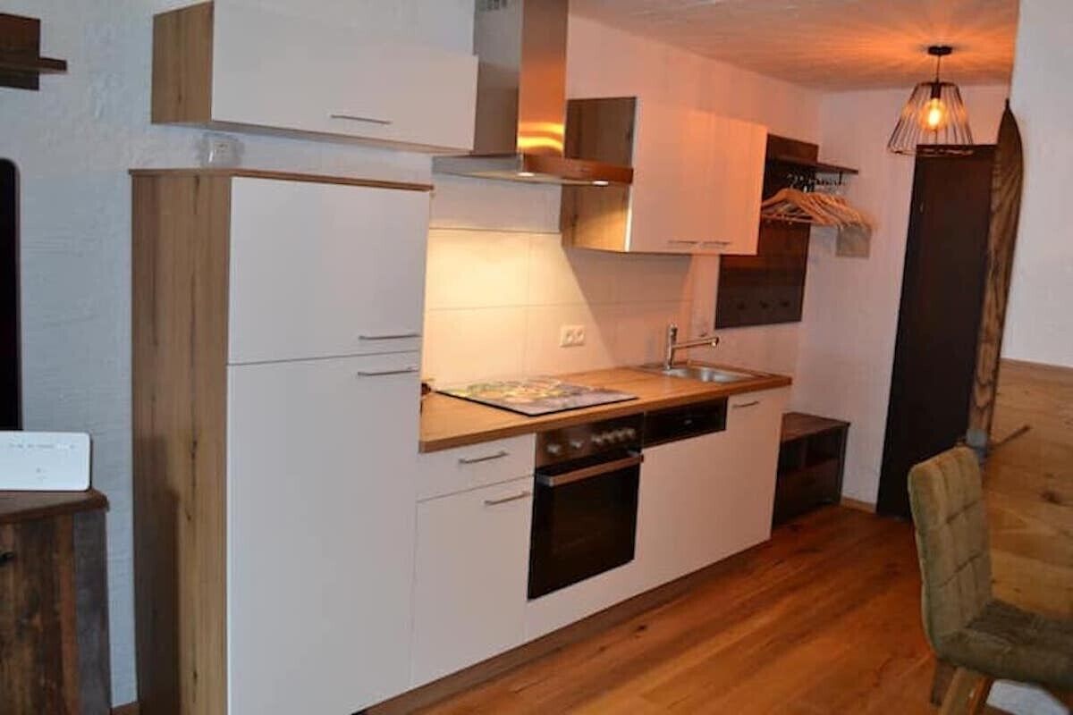 A compact kitchen with white cabinets, a wooden countertop, and a built-in oven.