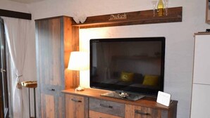 Una habitación con un armario de madera, un televisor, una lámpara y un cartel en el armario.