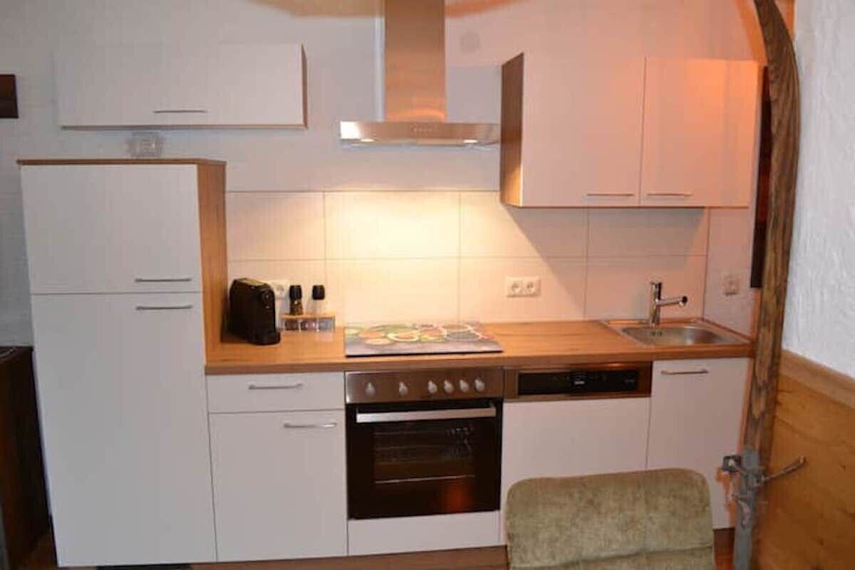 A compact kitchen with white cabinets, a stove, a dishwasher, and a small countertop area.