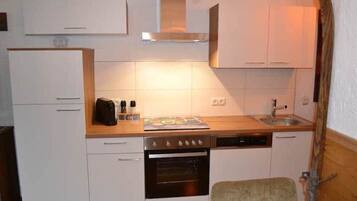 A compact kitchen with white cabinets, a stove, a dishwasher, and a small countertop area.