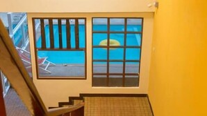 A staircase leading to a pool area with a view through a window. - Guyana Saikaew (Rayong)