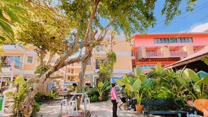 A courtyard with a tree, benches, and potted plants. - Guyana Saikaew (Rayong)